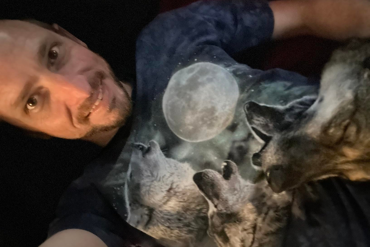 Person wearing a t-shirt with a graphic of wolves and a moon.